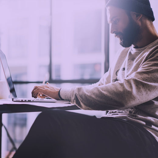 Man with in deep concentration wearing a beanie hat writing content on his laptop