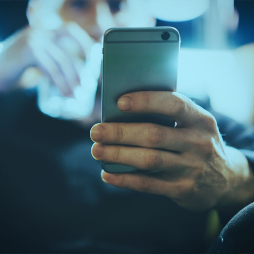 Man sitting on a chair checking websites on his phone